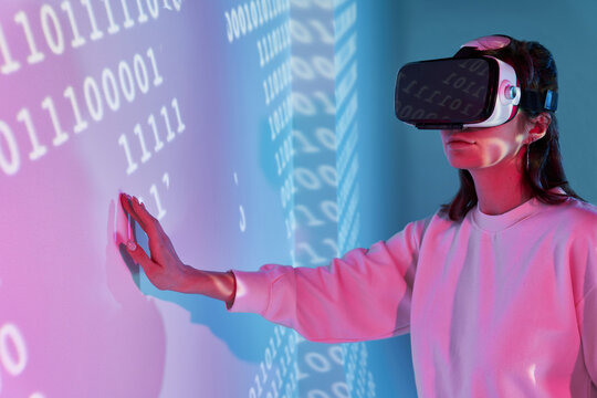 Woman in VR headset near wall with binary code