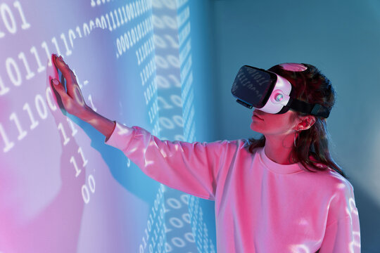 Woman in VR headset near wall with binary code