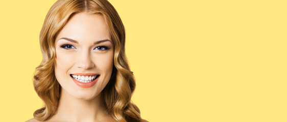 Portrait of happy smiling cheerful amazed young woman, isolated over yellow color background. Image of blond girl at studio. Dental health care concept. Copy space.
