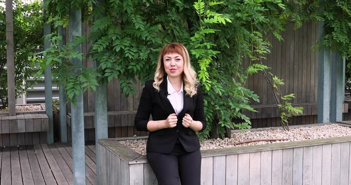 a beautiful girl with long blonde hair in a business suit gives an interview. blogger. journalist. news. A young business woman gives interviews about her company to journalists. an interview in a par