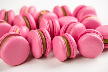 Macarons closeup on white wooden background. Sweet and colourful pink french macaroons. Cooking at home.