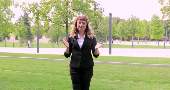 a beautiful girl with long blonde hair in a business suit gives an interview. blogger. journalist. news. A young business woman gives interviews about her company to journalists. an interview in a par