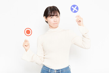 白い背景の前に立ってOKとNGのプラカードを見せている女性