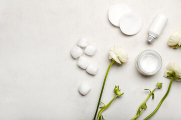 Composition with cosmetic products, cotton pads, balls and ranunculus flowers on light background
