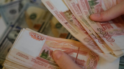 Women's hands hold Russian banknotes of five thousand rubles and count them with a fan with their fingers.