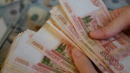 Women's hands hold Russian banknotes of five thousand rubles and count them with a fan with their fingers.