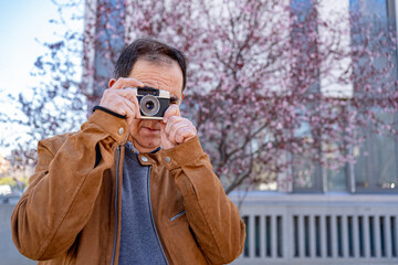 Older man is photographed while shooting with his old film camera.