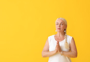 Meditating mature woman on color background