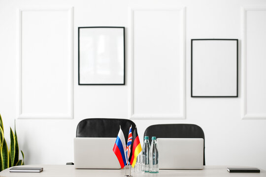 Modern laptops, Russian, British and German flags on table in light meeting room