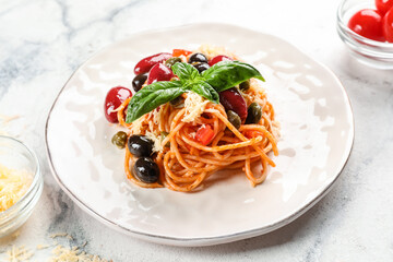 Plate with delicious Pasta Puttanesca and basil on white background