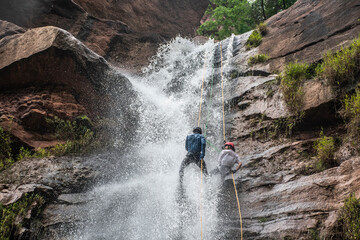 rappelling or torrentism in waterfall descending on ropes