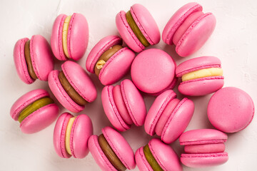 Obraz na płótnie Canvas Macarons closeup on white wooden background. Sweet and colourful pink french macaroons. Cooking at home.