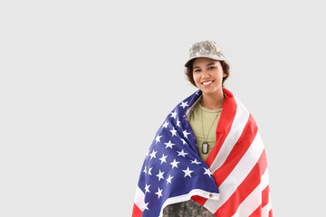 African-American female soldier with USA flag on light background