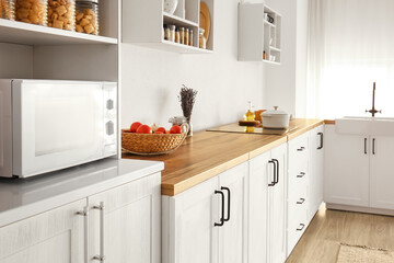 Interior of light modern kitchen with white counters and basket