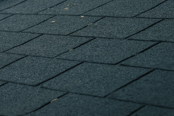 Obraz premium Bitumen roof tiles on a roof stacked together on an already worn out roof.