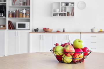 Basket with apples and grapes on dining table in kitchen