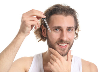Young man using serum for skin care on white background