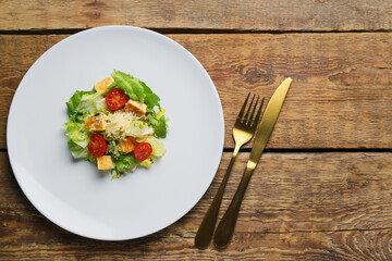 Plate with tasty vegan Caesar salad on wooden background