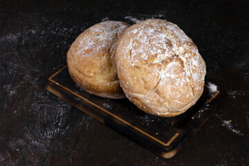Fresh homemade crisp bread. Healthy baked bread on rustic cutting board over black wooden table.