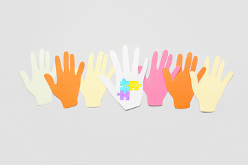 Paper human palms with drawn puzzle pieces on light background. Concept of autistic disorder