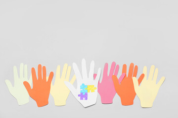 Paper human palms with drawn puzzle pieces on light background. Concept of autistic disorder
