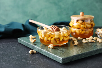 Board with sweet cashew nuts in honey on table