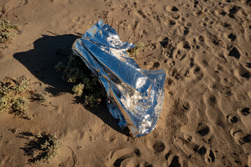 Silver space blanket on the sand view from above.