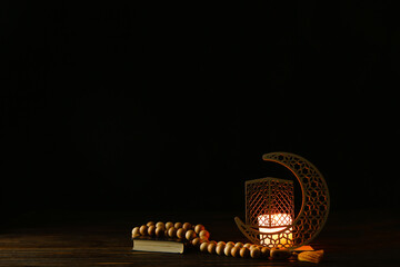 Fototapeta na wymiar Arabic candle holder with glowing candle, Quran and tasbih on dark background