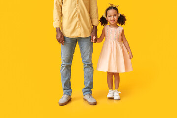 Little African-American girl and her father on yellow background