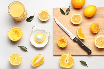 Ceramic juicer, glass of juice, lemon and oranges on light background
