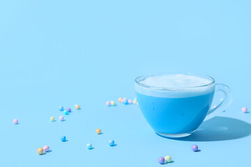 Cup of delicious matcha tea on blue background