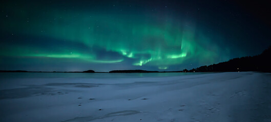 Moonlight and dancing northern lights over frozen lake. Farnebofjarden national park in north of sweden.
 