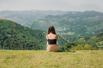 The girl traveler enjoys the view of the mountains, sitting on her back. High quality photo