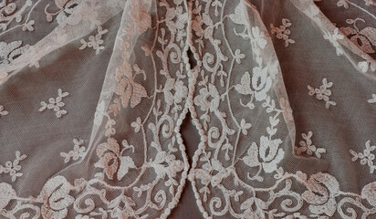 Spanish lace veil, mantilla, shawl or covering draped with traditional old design showing floral motif in delicate net pattern. This is a closeup of threads in white.