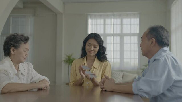 Holiday concept of 4k Resolution. Asian families take turns discarding cards on the table while playing games at home. Family gambling games.