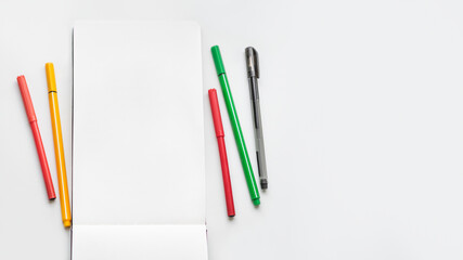 Top view on clear page of notebook. Mock up photo with notepad and colorful markers on white table. Workplace of artist.