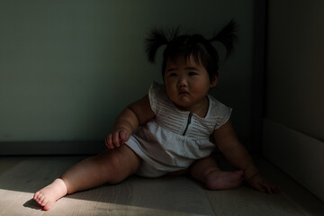 Asian baby sitting in deep shadows