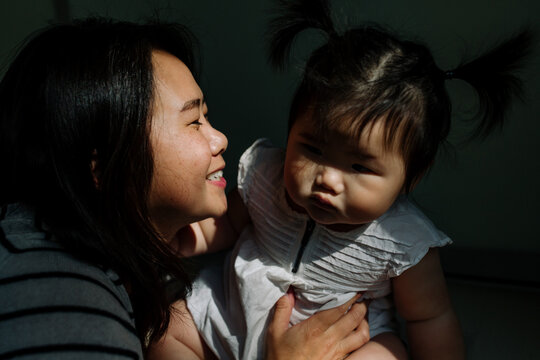 Smiling Asian mom and baby in pocket of light