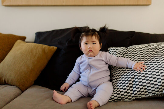 Asian baby wearing sleeper on couch