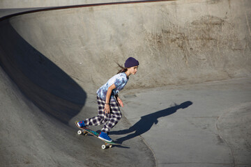 Teen skater riding skateboard in bowl 