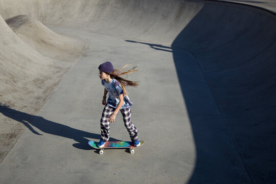 Teen skater riding skateboard in bowl 