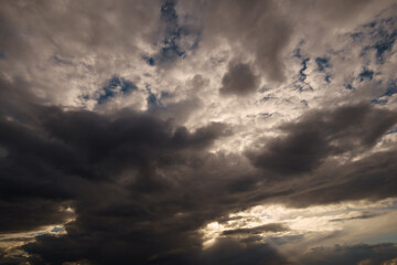 Naklejka na ściany i meble dark dramatic sky, bright sunlight and black silhouette of clouds as background