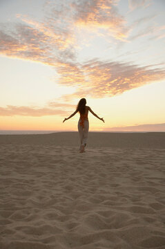 Woman walking on beach with arms open and extended