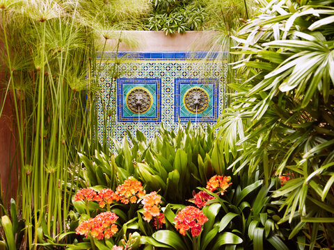 Tiled water fountain with lush tropical plants at spa.