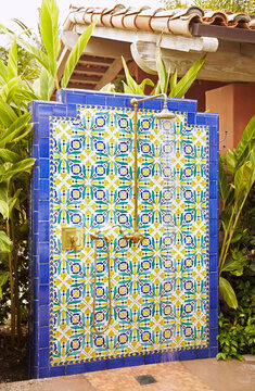 Tiled outdoor shower with lush tropical plants at spa.