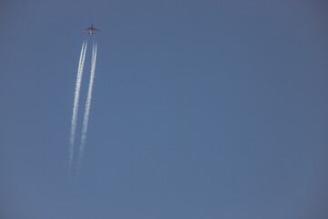 A plane crossing the left of the picture wiew from below, jet in high altitude in blue sky....
