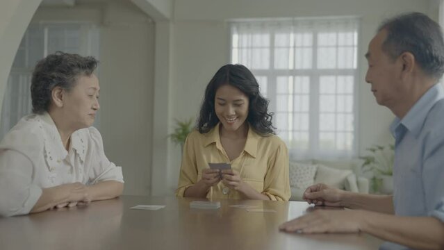 Holiday concept of 4k Resolution. Asian families take turns discarding cards on the table while playing games at home. Family gambling games.