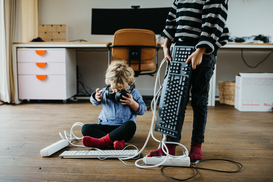 Two kids playing with electronic items at home
