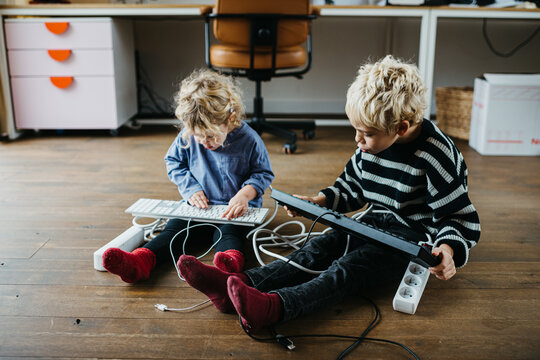 Siblings playing with computer keyboard at home