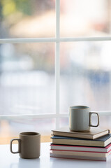 Books and coffee on desk by the window